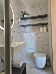 a white bathroom with a toilet and a sink at Apartments Zanic on The Beach in Podstrana