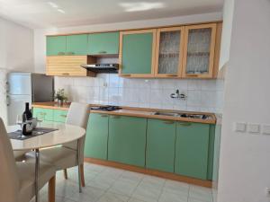 a kitchen with green cabinets and a table at Apartments Zanic on The Beach in Podstrana