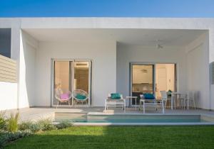 a patio with three chairs and a table and a yard at Splash Suites with Private Pools in Nikiana