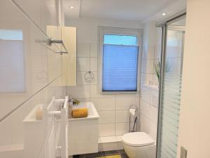 a white bathroom with a toilet and a window at DeNi's Ferienwohnungen in Klotten +32 photos