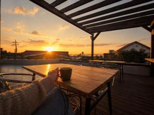 a wooden table and chairs on a deck with the sunset at There Bengdi in Jeju