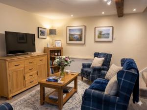 a living room with two chairs and a television at Coach House Hideaway in Warminster