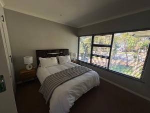 a bedroom with a large bed and two windows at Prime location in Welgemoed in Welgemoed