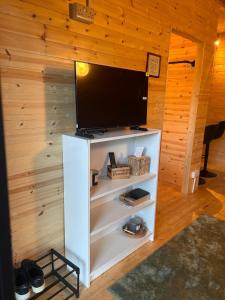 a flat screen tv on a white stand in a room at Tobys Lodge in Laragh