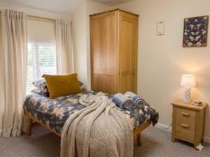 a bedroom with a bed and a wooden cabinet at Coach House Hideaway in Warminster