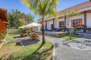 a patio with a table and umbrella in a yard at Wigus Villa Melasti in Ungasan