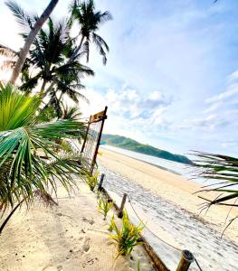 a chair on a beach with palm trees and the ocean at The Sanctuary in El Nido