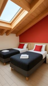 two beds in a room with red walls at ValtellinaHome in Villa di Tirano