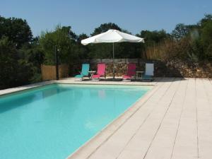 a swimming pool with chairs and an umbrella at La Zénitude in Les Lèches