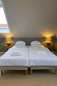 a bedroom with two beds with white sheets and two lamps at Klippen Hotel - Skt Jørgens Gaard in Gudhjem