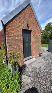 a brick building with a green door on it at La maison du hérisson in Flines-lès-Mortagne