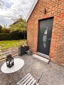 a black garage door with a white table and a bench at La maison du hérisson in Flines-lès-Mortagne