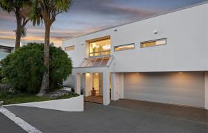 a white house with a balcony and palm trees at Stillpoint Retreat in Motungarara