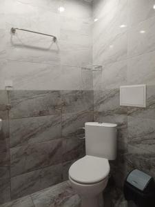 a bathroom with a toilet and a marble wall at Апартаменти и стаи Анхиало in Pomorie +44 photos