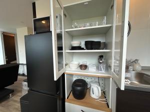 a kitchen with a black refrigerator and white shelves at Villa ORAN in Nakafurano