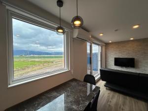 a living room with a piano and a large window at Villa ORAN in Nakafurano