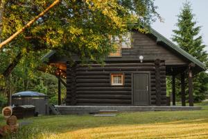 a log cabin with a garage in front of it at River House in Nītaure