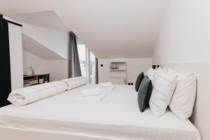 a white bedroom with a large white bed with white pillows at Babin bed&breakfast in Pirovac