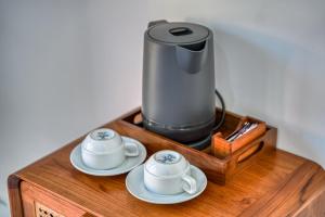 a coffee maker and two cups on a wooden table at Wigus Villa Melasti in Ungasan