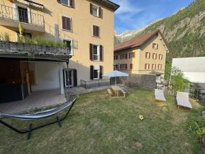 a yard with two chairs and a table and an umbrella at Blue Sky Apartments in Göschenen
