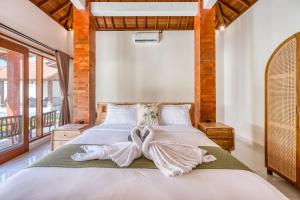 a bedroom with a large bed with two hearts towels at Wigus Villa Melasti in Ungasan