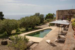 a swimming pool with chairs and an umbrella at Il Mulino di Scauri in Pantelleria