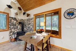 ein Esszimmer mit einem Holztisch und einer Steinwand in der Unterkunft Deer Pine Cabin in Bigfork