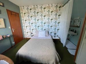 a small bedroom with a bed and a curtain at Chambre à louer face a la plage de Beaumer in Carnac
