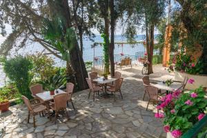 a patio with tables and chairs next to the water at Empress Corfu in Perama