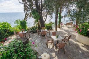 a patio with tables and chairs next to the ocean at Empress Corfu in Perama
