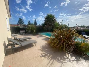 a patio with two lounge chairs and a swimming pool at CHAMBRE D HÔTE CHEZ Nath in Sadirac