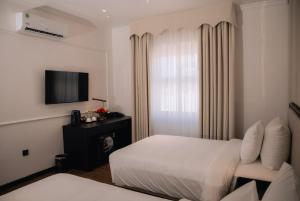 a hotel room with a bed and a television at The Manor Hotel in Nam Ðịnh
