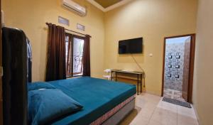 a bedroom with a bed and a television and a desk at Rian Kost - Hotel Penginapan Murah Pusat Kota Palembang in Palembang
