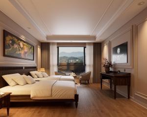 a bedroom with two beds and a desk and a window at Dalabiang Hotel in Da Lat