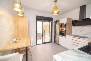 a kitchen with white cabinets and a wooden counter top at Casa flor del Rocio in La Rinconada +37 photos