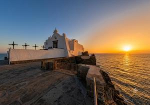 a church on the edge of the ocean at sunset at Little House Forio in Forio d'Ischia