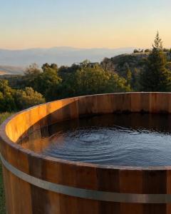 a wooden tub filled with water in a field at Calma Hermon Guest Rooms in Neve Ativ +17 photos