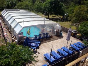a swimming pool with blue chairs and a tent at Villa Les Martinets-Chambres Climatisées-Parking Privé-Piscine-Jacuzzi-Brise Fraîche de la Montagne in Le Poujol-sur-Orb