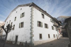 a large white building with windows on a street at Appartement ambiance vieux chalet in Sembrancher