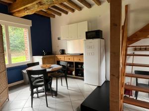 a kitchen with a table and a white refrigerator at Le champ de l alouette in Bec-de-Mortagne
