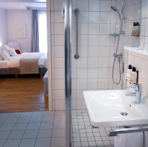 un bagno con doccia, lavandino e letto di Hotel Simoncini a Lussemburgo Altre 32 foto