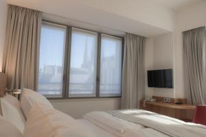 una camera d'albergo con un letto e grandi finestre di Hotel Simoncini a Lussemburgo