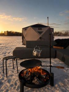 a tent with a fire in front of it in the snow at Harju-Hill Villa in Rovaniemi
