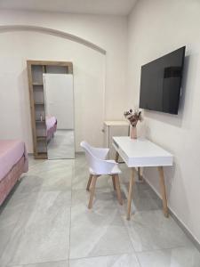 a room with a white table and a tv on a wall at Suite in centro in Aversa