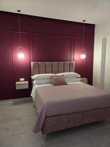 a bedroom with a large bed with purple walls at Suite in centro in Aversa