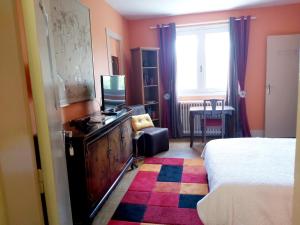 a bedroom with a bed and a dresser with a television at Villa Tronçais in Saint-Bonnet-Tronçais