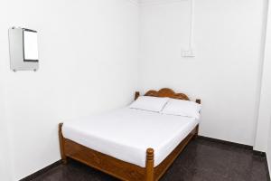 a bed in a room with white walls at Samarth Villa in Akalkot