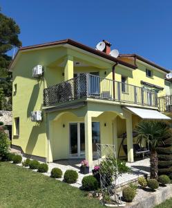 a yellow house with a balcony and a yard at Matea in Plomin