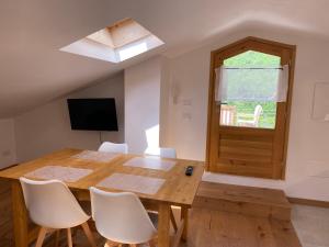 a dining room with a wooden table and white chairs at Xenìa in Villalago