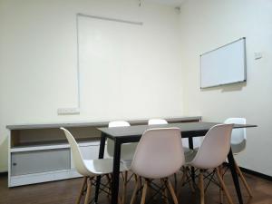 a classroom with a black table and white chairs at Windsor Lane Hostel Ipoh in Ipoh
